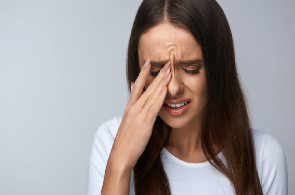 a woman experiencing eye pain holds her eye