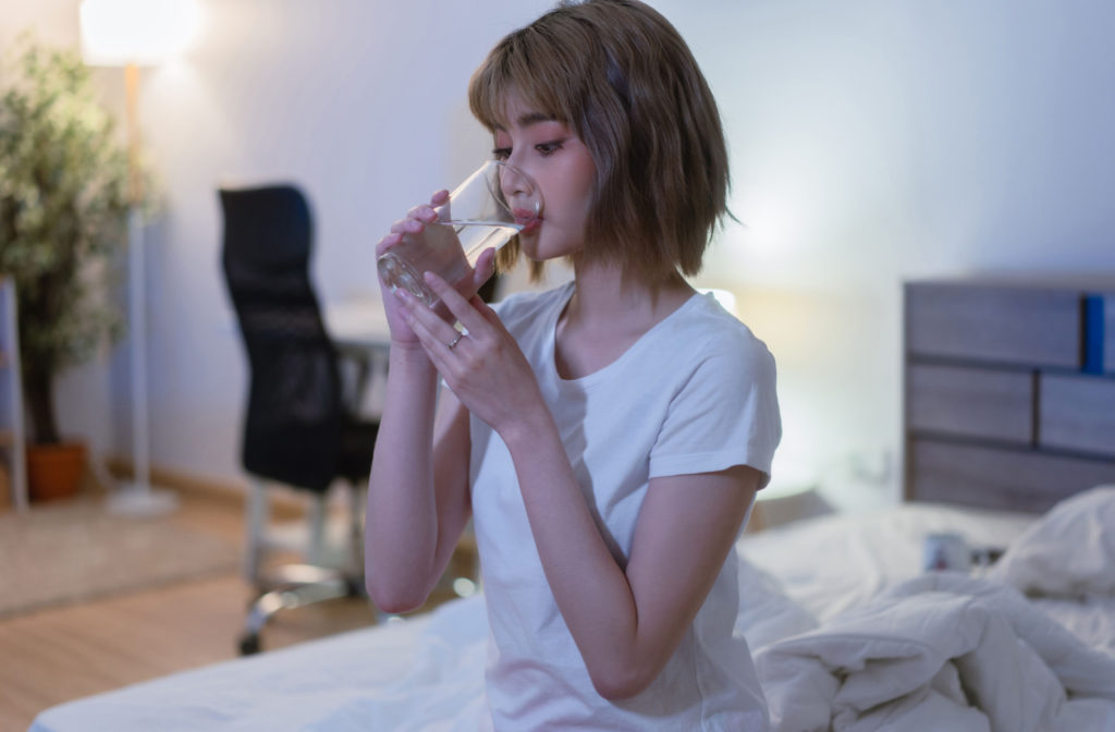 A young women is drinking a glass of water before sleeping.