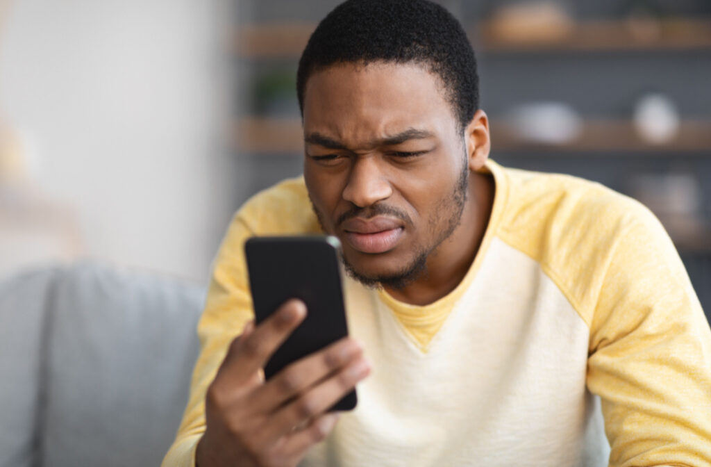 A man sitting in a living room squinting at his phone