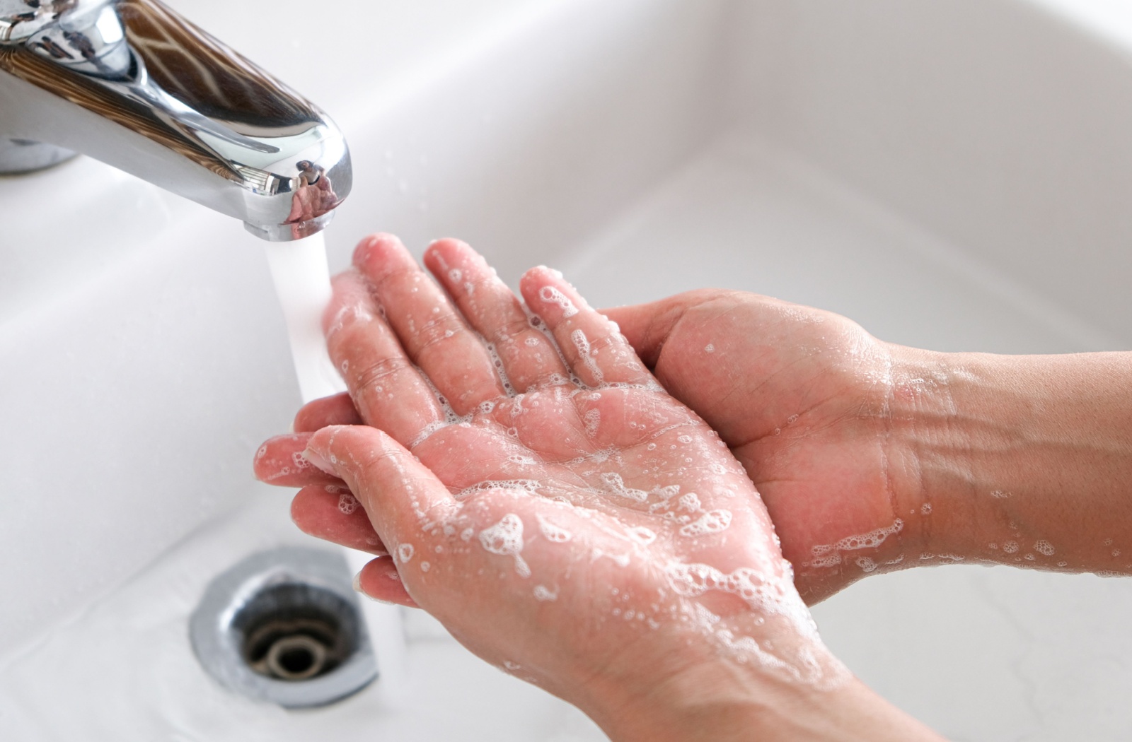 A close-up of a person's hands being washed using running water and soap.
