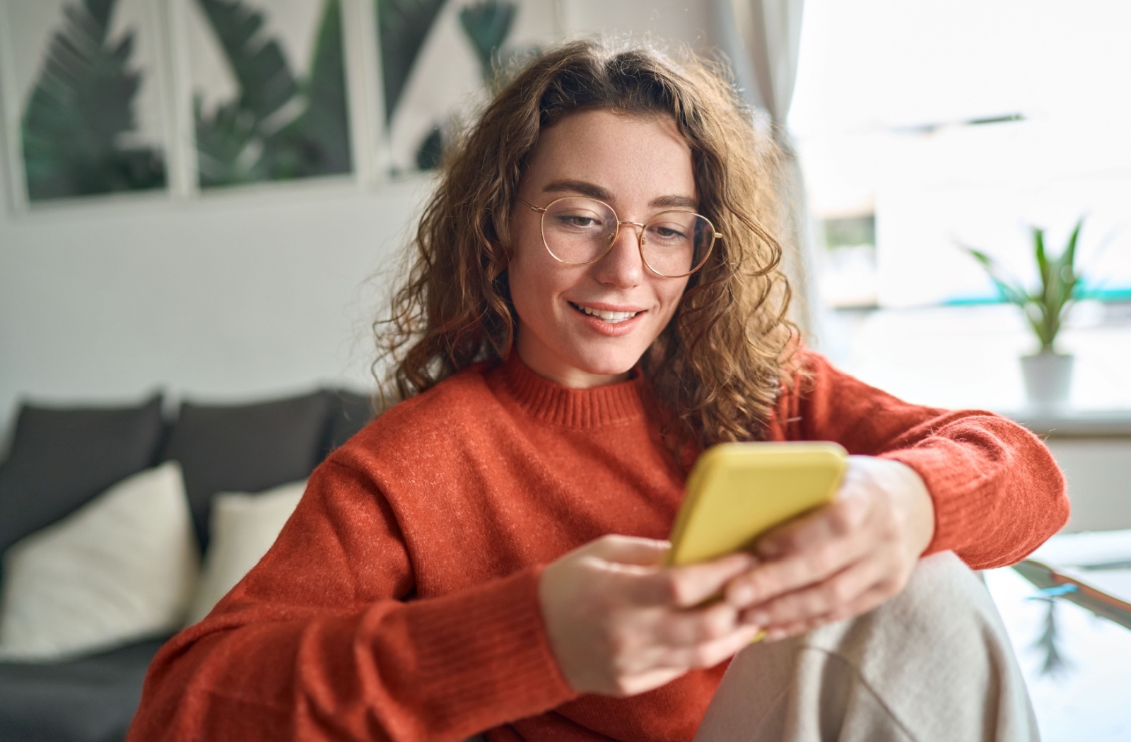 A woman is reading the contents on her smart phone with ease with her corrective lenses for hyperopia.