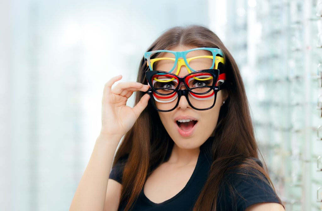 A young woman wearing multiple pairs of glasses all with different lens types.