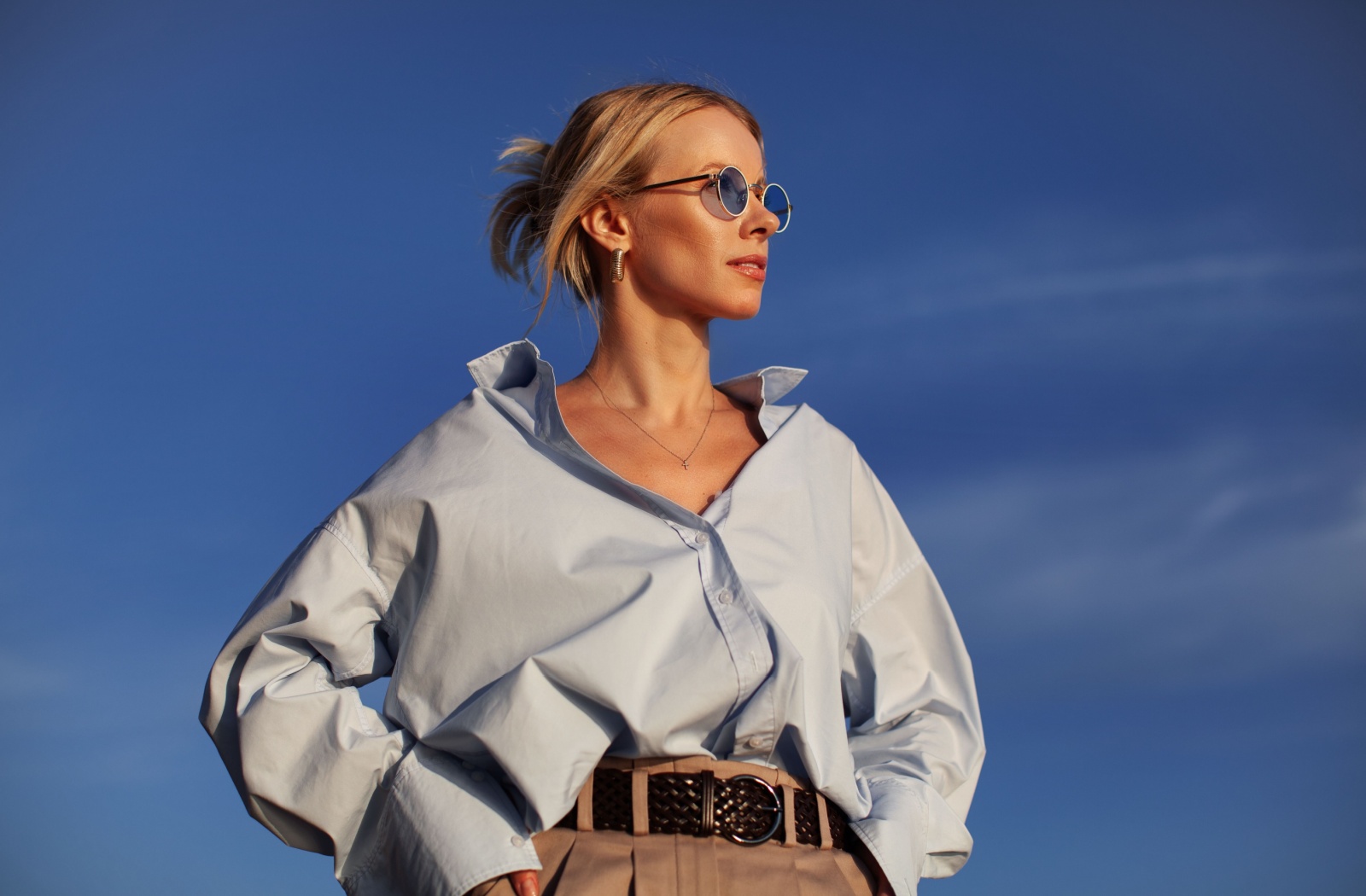 A young woman standing outside in polarized sunglasses to help protect her eyes from glare.