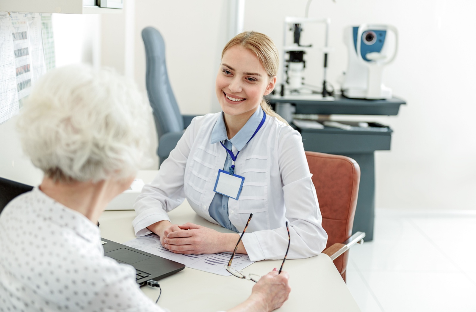 An optometrist smiling during an appointment while listening to her patient discuss her dry eye symptoms.
