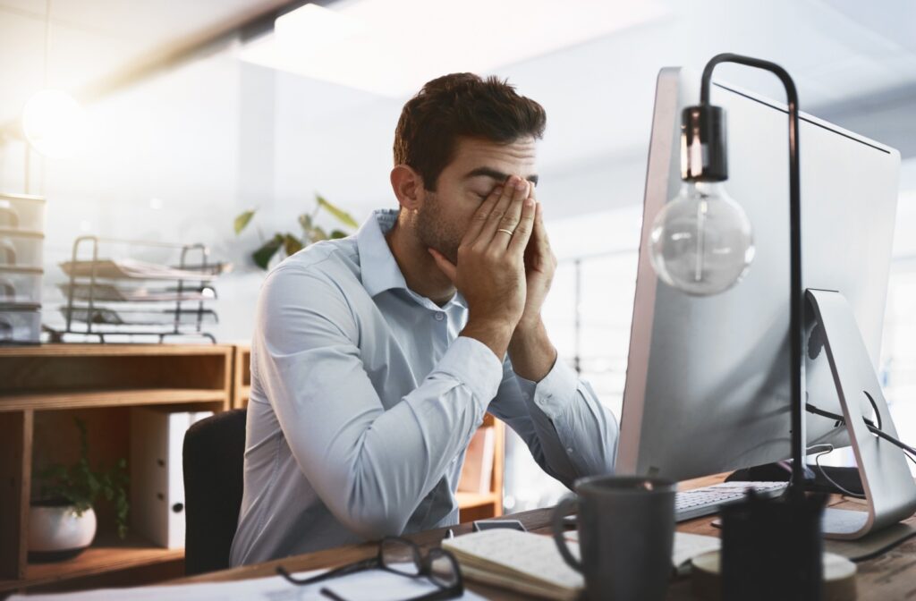 A person working in the office rubbing their sore eyes while experiencing eye strain