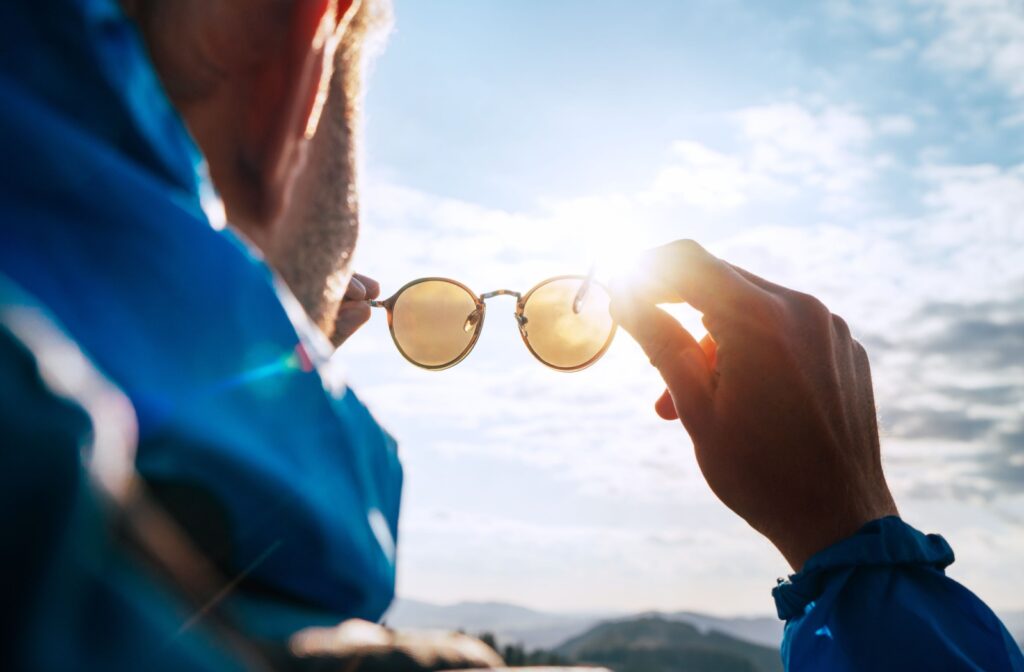 Person holding polarized sunglasses up to the sunlight to demonstrate lens clarity and glare reduction.
