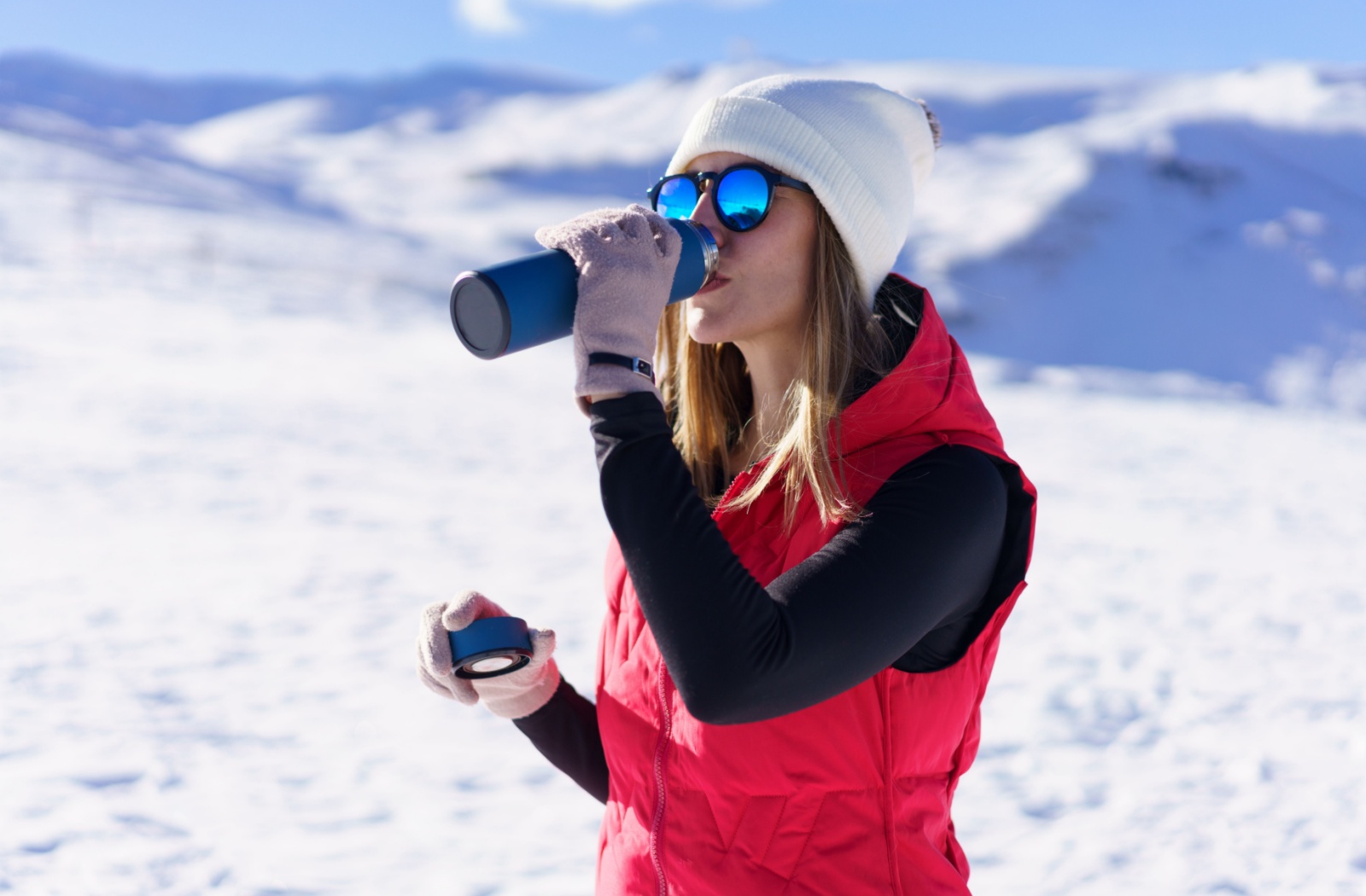 Woman wearing polarized sunglasses on a snowy mountain, with lenses helping to reduce glare and protect her eyes from the sun’s reflection off the snow.