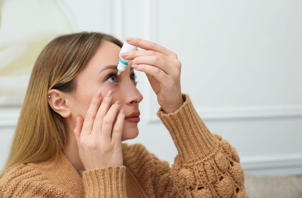 A person uses eye drops for relief, applying the solution while looking upward.