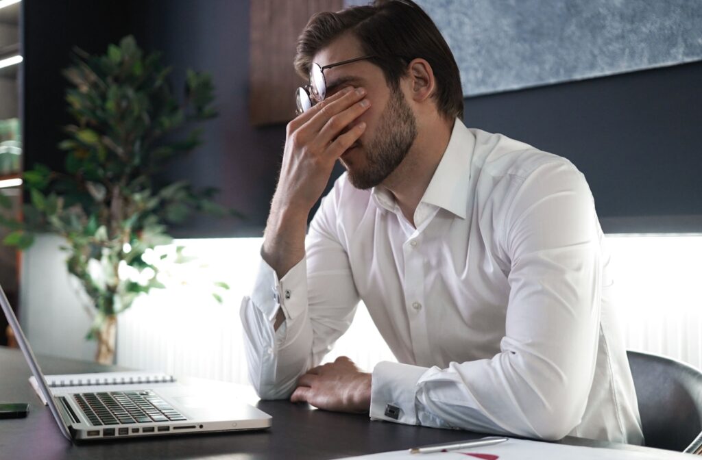 A person rubbing their eyes due to the irritation experienced from meibomian gland dysfunction.